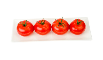 Four red ripe tomatoes on white plate.