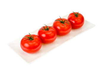 Four red ripe tomatoes on white plate.