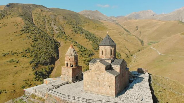 Slow motion revealing view of Kazbegi trinity church on hill with background of caucasus mountains.Historical sites and georgian culture concept