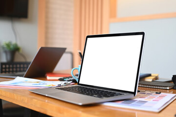 An open laptop computer with blank screen on wooden office desk.