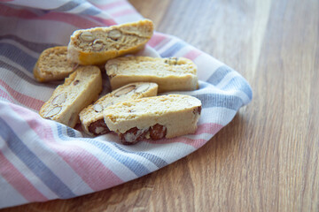Sweet biscotti cookies with nuts and a striped kitchen towel on wooden background. Side vie