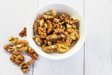 walnuts in the white bowl close. peeled walnuts on white colored old vintage wooden backdrop.