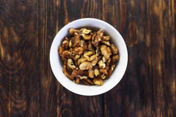 peeled walnuts in the white bowl close on brown old wooden table. healthy food concept