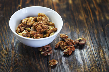 peeled walnuts in the white bowl close on brown old wooden table. healthy food concept