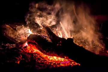 Close-up of a log burning in a fire with smoke