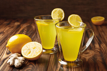 Two glass cup of lemon ginger lemonade and ingredients on wooden rustic background remedy for...