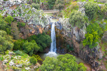 Fototapeta na wymiar Waterfall with Rain and Snow waters plummeting down the stream, surrounded by lush green nature, Aerial view.