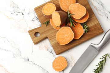 Composition of Fresh ripe sweet potatoes and rosemary spice on table against marble background