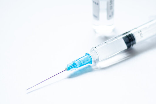 Syringe With Needle Without Cover Or Top, Vial Or Phial On A White Empty Space Background Ready To Be Used. Covid Or Coronavirus Vaccine Or Monoclonal Antibodies Background, Close Up