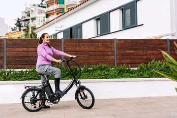 Fototapeta na wymiar 40-year-old woman riding her electric bicycle through the streets of the city