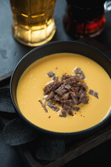 Bowl of bacon and cheese dipping sauce, vertical shot with beer mugs in the background