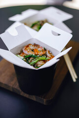 noodles with tiger prawns and sesame seeds in paper box