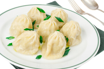 White plate with boiled khinkali, green onions.