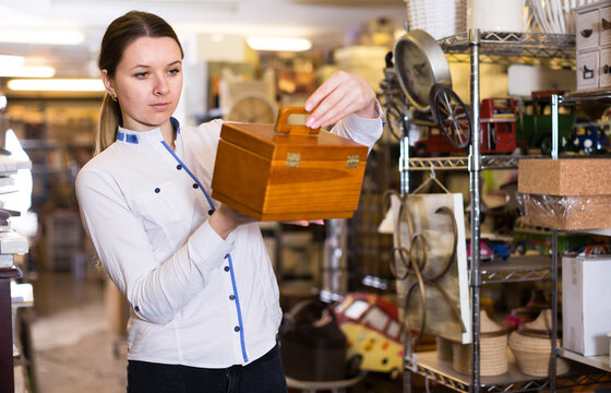 Young woman is standing with wooden medicine chest in store