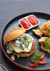 Burger on a plate  with chips and sauce on black plate
