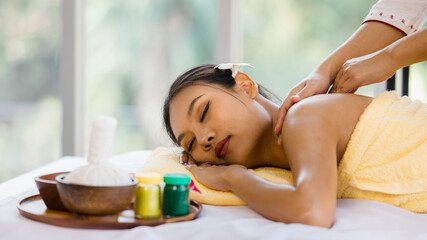 Obraz na płótnie Canvas beautiful Asian woman enjoy getting an oil massage happily in a spa. Relaxing and healing with Thai massage and aroma oil. Body care and treatment, alternative medicine concept