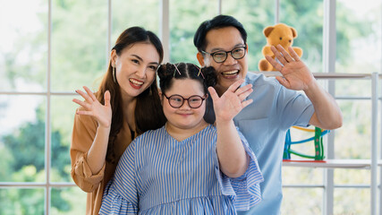 happy Asian family father mother and handicapped daughter with down syndrome standing and smiling...