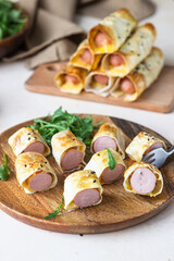 Homemade sausages in dough with sesame served with tomato sauce, light stone background. Pigs in blanket. Fast food.