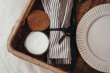 Wooden wicker tray with dishes, plate in boho interior 