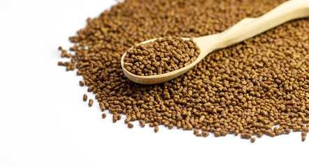 Buckwheat tea in a wooden spoon on a white background. Isolate. Buckwheat tea close-up macro photography. Scattered buckwheat tea pellets on white background.