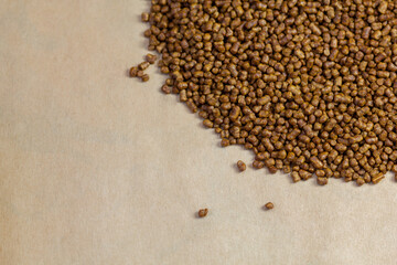 Buckwheat tea on a brown background copy space. Isolate. Buckwheat tea close-up macro photography. Scattered buckwheat tea pellets on brown background top view.