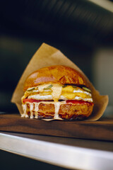 juicy burger in brown paper on a wood board