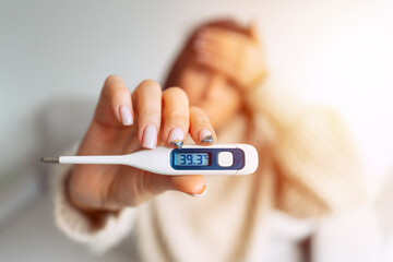 Ill woman with a high fever showing thermometer with high body temperature 39.3