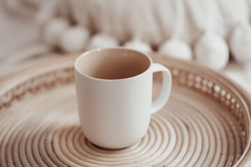 White ceramic mug in boho interior on a wicker tray