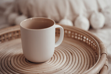 White ceramic mug in boho interior on a wicker tray