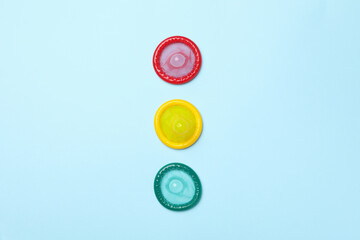 Multicolored condoms on blue background, top view