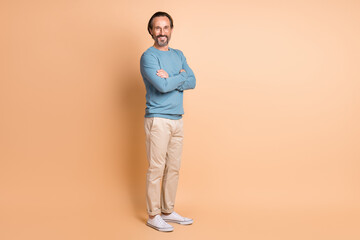 Fototapeta na wymiar Full length photo of man folded arms wear glasses blue sweater pants sneakers isolated beige color background