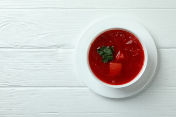 Bowl of borscht on white wooden background