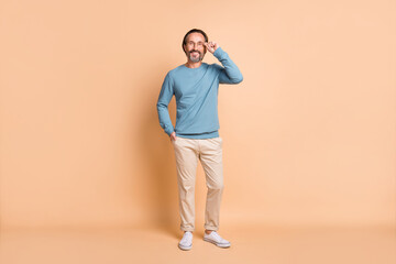 Photo portrait full body view of man touching glasses isolated on pastel beige colored background