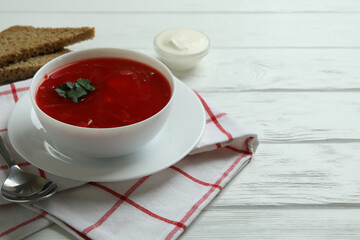 Concept of tasty eating with borscht on white wooden background