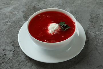 Bowl of tasty borscht on gray background