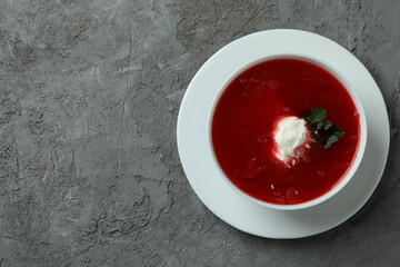 Bowl of tasty borscht on gray background