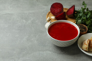 Concept of tasty eating with borscht and ingredients on gray table