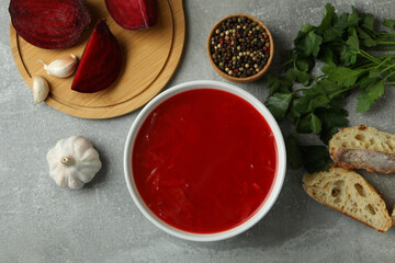 Concept of tasty eating with borscht and ingredients on gray table