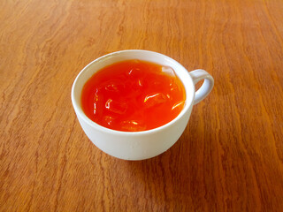 Orange juice and ice in a white glass on a wooden table