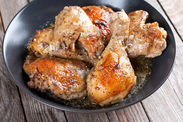 Baked chicken in a bowl on wooden table, homemade food