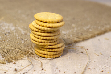 Fototapeta na wymiar Salty biscuit cracker on coarse linen cloth close up Narrow focus line, shallow depth of field