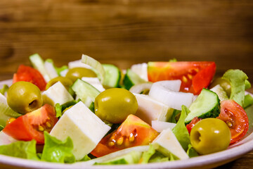 Ceramic plate with greek salad on wooden table