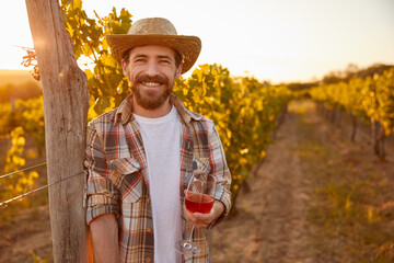 Cheerful farmer with wine resting on vineyard