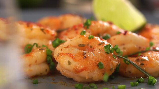 Close up of fried prawns in sweet and sour sauce with garlic spices and seasonings. Shrimps is sprinkled with green chopped onions. Macro food background. Seafood
