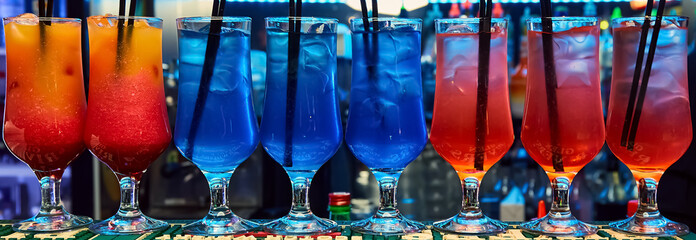 cocktails stands on a bar in a nightclub. Two straws sticking out of the cocktail