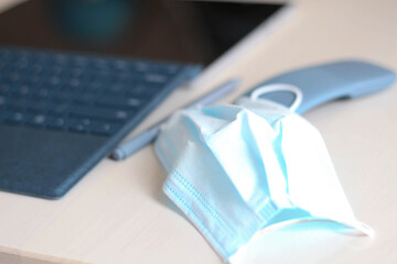 Smart working during coronavirus epidemic. Medical face mask on on top of gray computer laptop on table. Business, medicine, learning, sale strategy