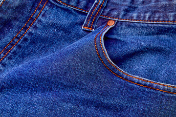 Fototapeta premium Blue denim jeans background pocket with seam and orange thread stitches.