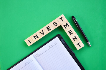 'Investment' word on wood block with green background flat lay concept.