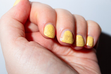 Fingers with a damaged yellow gel polish coating. Selective focus. Close-up. White background.