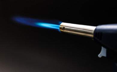 Blue flame from a gas torch burner on black background - obrazy, fototapety, plakaty